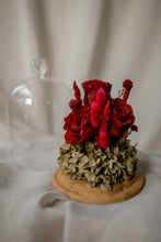 Load image into Gallery viewer, Small floral arrangement with red and burgundy flowers on a wooden base against a neutral background