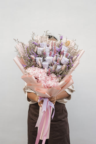 A beautiful bouquet of 20 preserved roses in a mix of lilac and pink, with lush preserved hydrangeas surrounding the base, presented against a soft, neutral background.