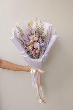 Load image into Gallery viewer, Bouquet of flowers wrapped in purple paper with a ribbon, held by a person against a plain background
