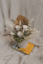 Load image into Gallery viewer, Vase arrangement of flowers in a white vase on a book with a textured beige background,
