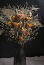 Load image into Gallery viewer, Dried floral arrangement with orange flowers and pampas grass in a black vase on a dark background
