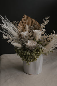 vase arrangement of dried flowers in a white vase on a dark background