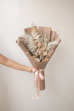 Load image into Gallery viewer, Bouquet of dried flowers wrapped in brown paper with a pink ribbon, held against a plain background.
